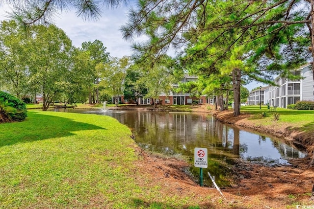 surrounding community with a water view and a lawn