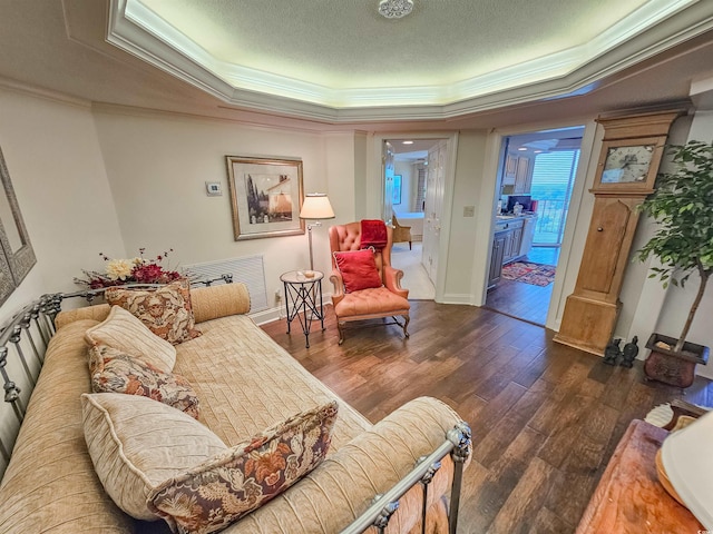 living room featuring a textured ceiling, a tray ceiling, dark hardwood / wood-style floors, and crown molding