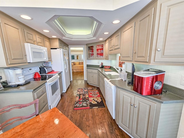 kitchen featuring tasteful backsplash, sink, white appliances, a raised ceiling, and dark hardwood / wood-style flooring