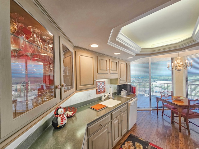 kitchen with dark wood-type flooring, a raised ceiling, dishwasher, sink, and a chandelier