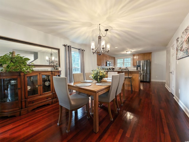 dining area featuring dark hardwood / wood-style floors, an inviting chandelier, and a healthy amount of sunlight