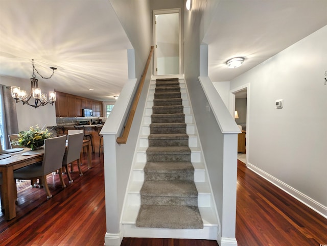 stairs with a chandelier and hardwood / wood-style flooring