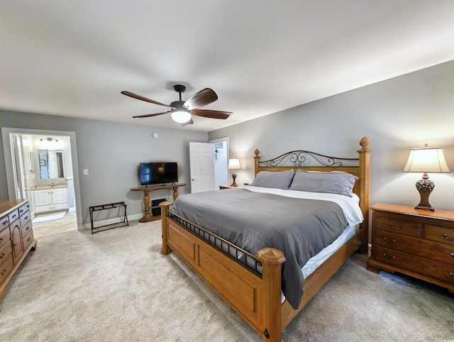 bedroom with ceiling fan, light colored carpet, and ensuite bathroom