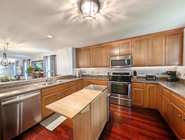 kitchen featuring stainless steel appliances, wooden counters, an inviting chandelier, sink, and dark wood-type flooring