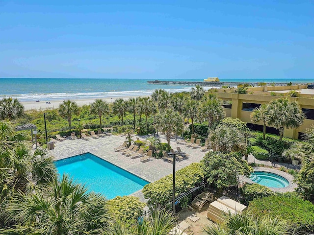 view of pool with a water view, a patio area, and a beach view