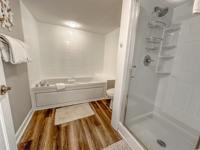 bathroom featuring toilet, wood finished floors, a bathtub, walk in shower, and baseboards