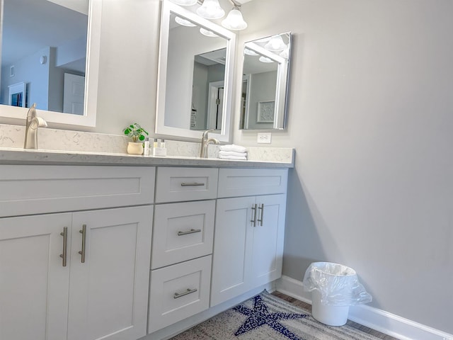 bathroom with double vanity, a sink, and baseboards