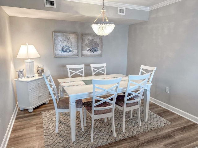 dining space featuring hardwood / wood-style floors, an inviting chandelier, and ornamental molding