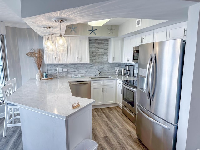 kitchen with white cabinets, visible vents, a peninsula, stainless steel appliances, and a sink