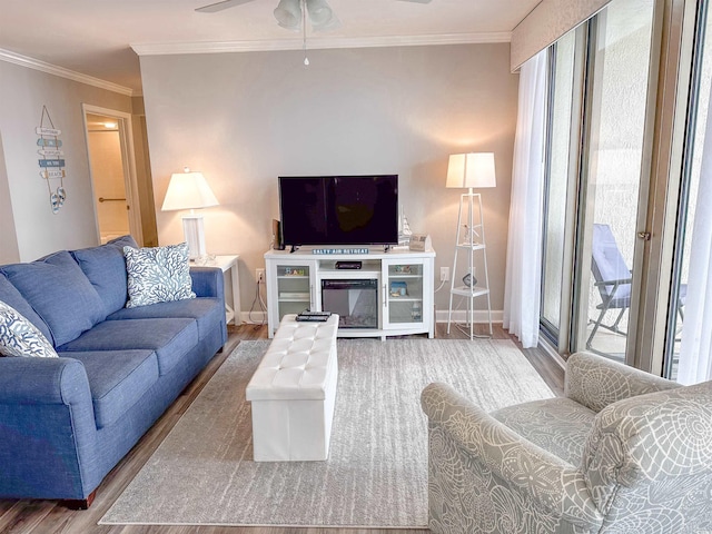 living room with baseboards, ceiling fan, wood finished floors, and crown molding