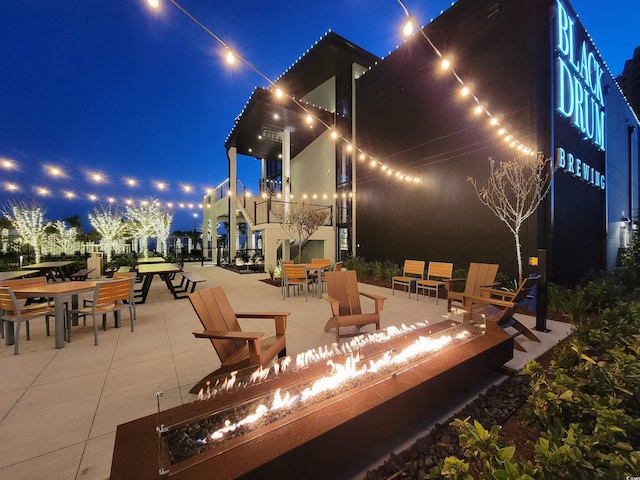 patio at night featuring an outdoor fire pit and outdoor dining area