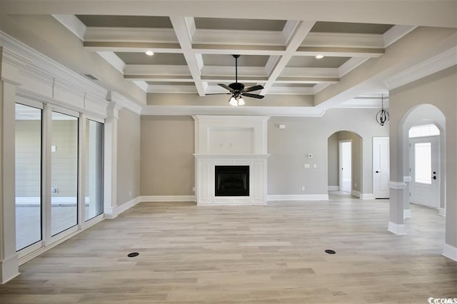 unfurnished living room featuring light wood-type flooring, coffered ceiling, beamed ceiling, and a healthy amount of sunlight