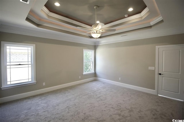 carpeted empty room featuring ceiling fan, ornamental molding, and a tray ceiling