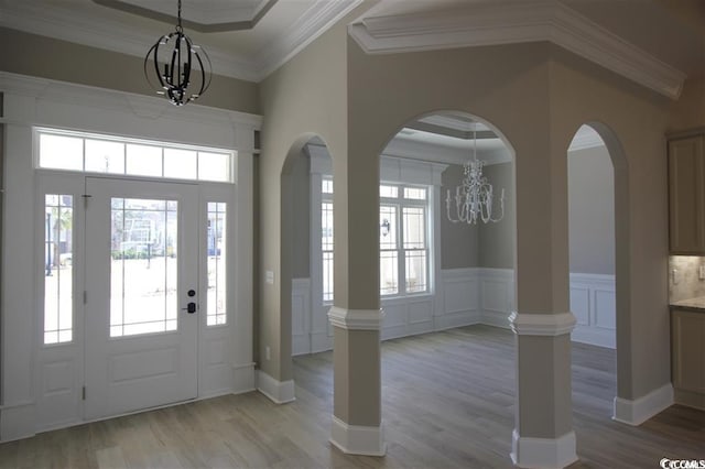 foyer entrance featuring light wood-type flooring, a raised ceiling, and a notable chandelier