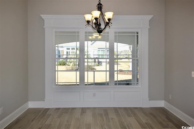 unfurnished dining area with plenty of natural light, a chandelier, and dark hardwood / wood-style flooring