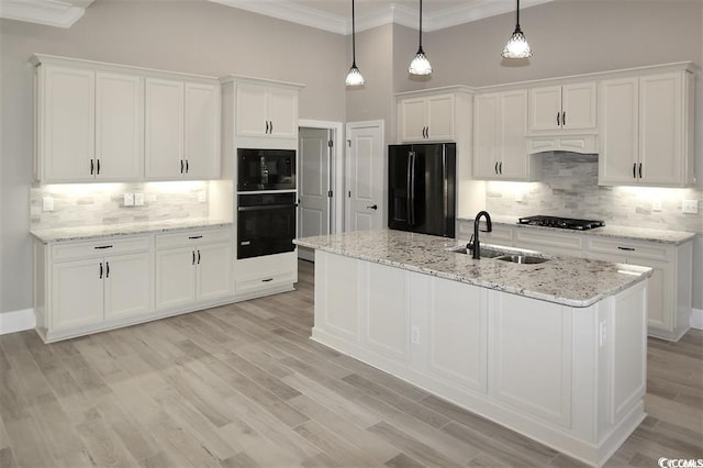 kitchen featuring crown molding, sink, black appliances, tasteful backsplash, and a kitchen island with sink