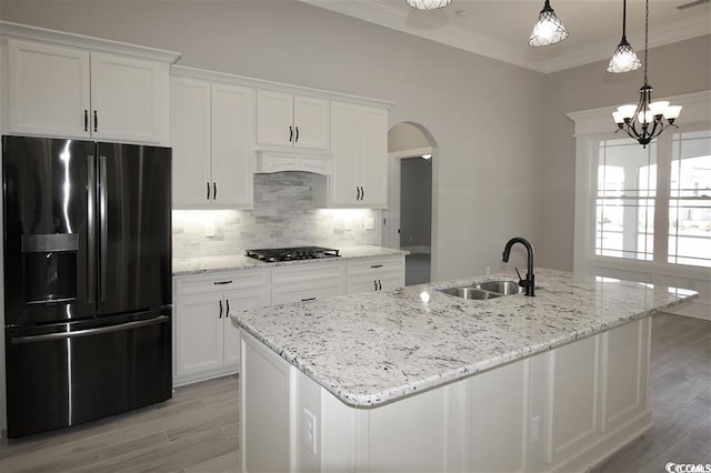 kitchen featuring crown molding, tasteful backsplash, an island with sink, and fridge with ice dispenser