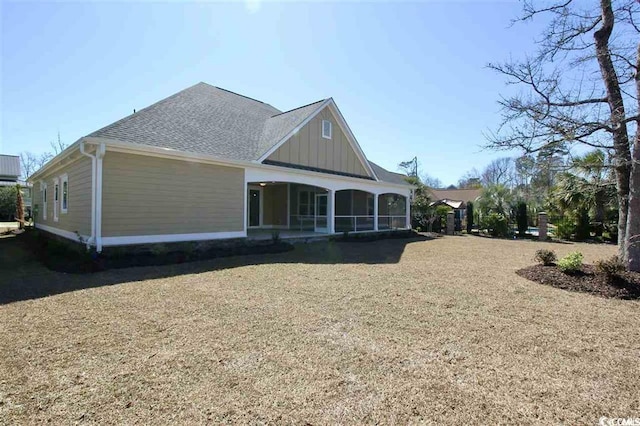 rear view of house with a sunroom and a lawn