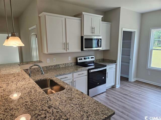 kitchen featuring sink, white cabinets, light hardwood / wood-style flooring, appliances with stainless steel finishes, and decorative light fixtures