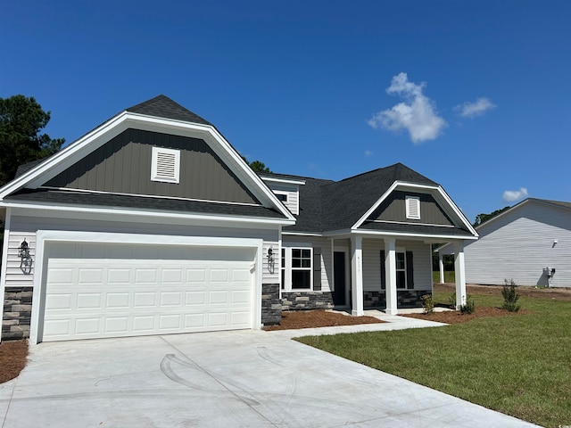 craftsman inspired home with covered porch, a front yard, and a garage