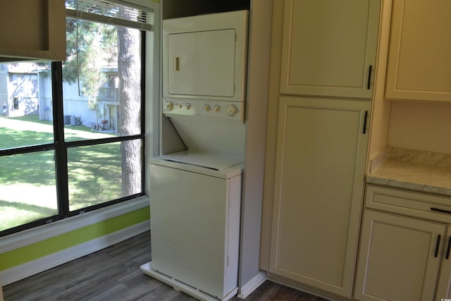 laundry room featuring dark wood-type flooring and stacked washing maching and dryer