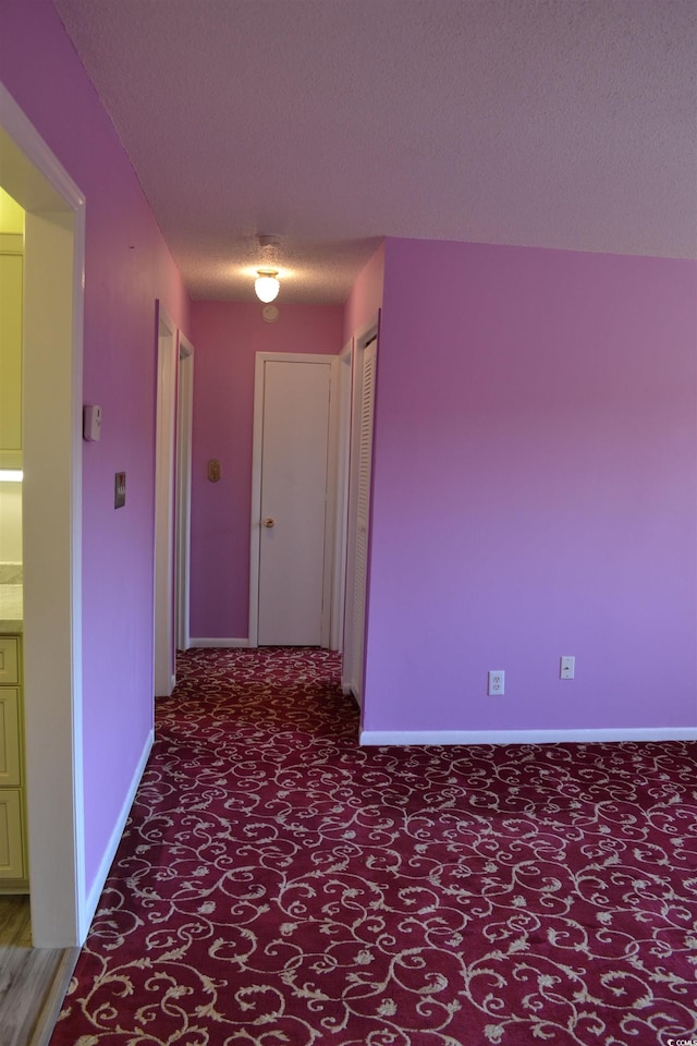 hall featuring a textured ceiling and carpet flooring