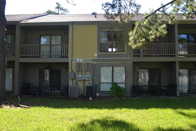 back of house with a balcony, a yard, and central AC