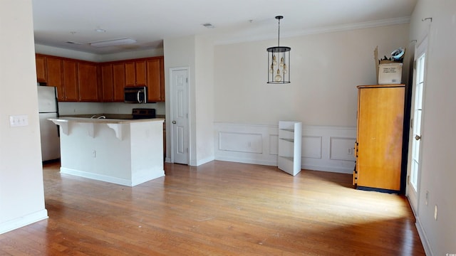 kitchen with a breakfast bar, hanging light fixtures, a center island, stainless steel appliances, and light wood-type flooring