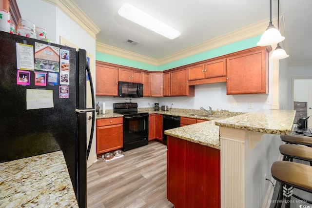 kitchen with a breakfast bar area, black appliances, light hardwood / wood-style flooring, kitchen peninsula, and ornamental molding