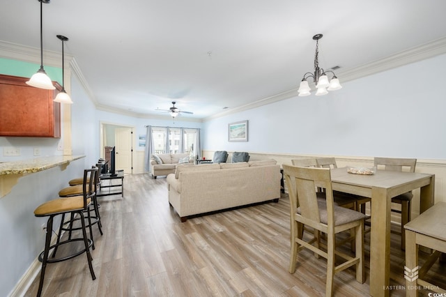 dining space with crown molding, ceiling fan with notable chandelier, and light hardwood / wood-style floors