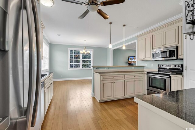 kitchen featuring appliances with stainless steel finishes, light wood-type flooring, cream cabinetry, crown molding, and decorative light fixtures