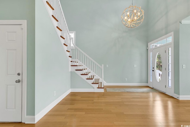 entryway with a chandelier, light hardwood / wood-style flooring, and a towering ceiling