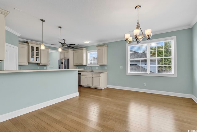 kitchen featuring hanging light fixtures, appliances with stainless steel finishes, light hardwood / wood-style flooring, ornamental molding, and cream cabinetry