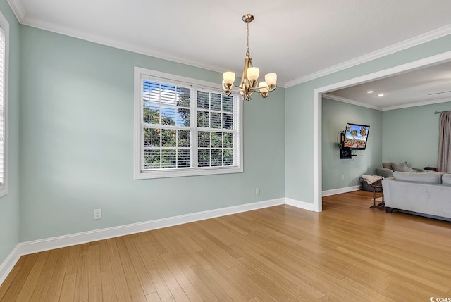 empty room with crown molding, light hardwood / wood-style flooring, and an inviting chandelier