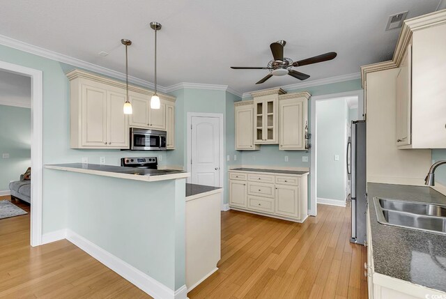 kitchen with appliances with stainless steel finishes, light wood-type flooring, pendant lighting, crown molding, and sink