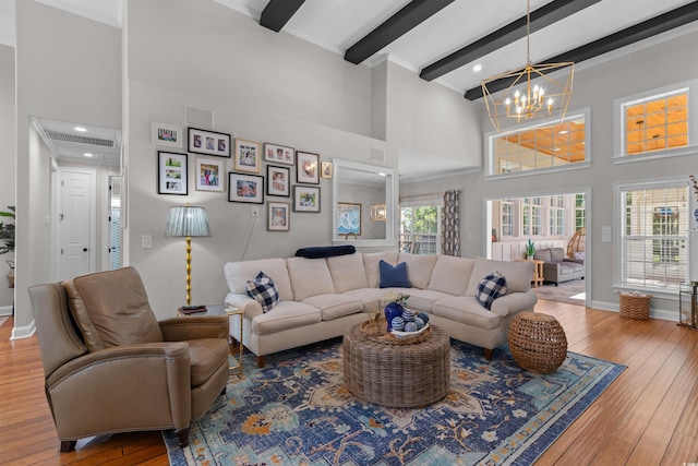 living room featuring a chandelier, wood-type flooring, a high ceiling, and beamed ceiling
