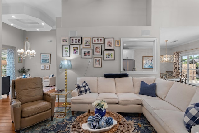 living room with crown molding, a high ceiling, an inviting chandelier, and hardwood / wood-style flooring