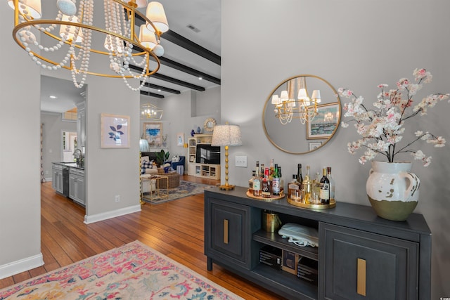 bar with visible vents, baseboards, an inviting chandelier, beamed ceiling, and wood-type flooring