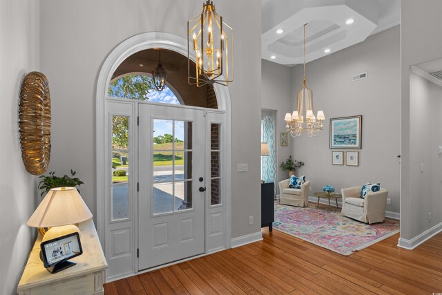 foyer with a high ceiling, wood-type flooring, and a chandelier