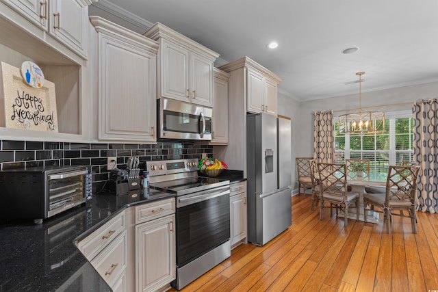 kitchen featuring a notable chandelier, backsplash, stainless steel appliances, hanging light fixtures, and light hardwood / wood-style floors