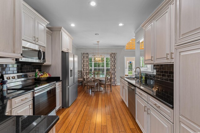 kitchen featuring a notable chandelier, light hardwood / wood-style flooring, stainless steel appliances, sink, and decorative backsplash