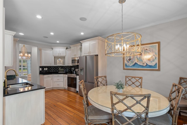 kitchen with light wood-type flooring, appliances with stainless steel finishes, backsplash, and sink