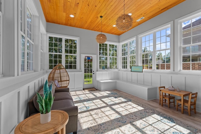 sunroom / solarium with visible vents, plenty of natural light, wood finished floors, and wood ceiling