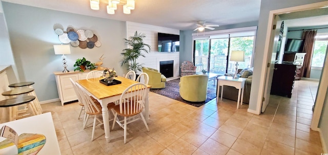 tiled dining space with a fireplace, a healthy amount of sunlight, and ceiling fan