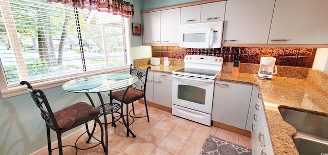 kitchen featuring white cabinets, sink, tasteful backsplash, light stone countertops, and white appliances