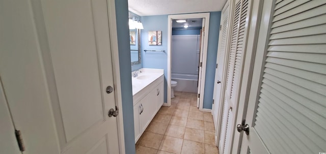 bathroom featuring tile patterned floors, vanity, toilet, and a textured ceiling