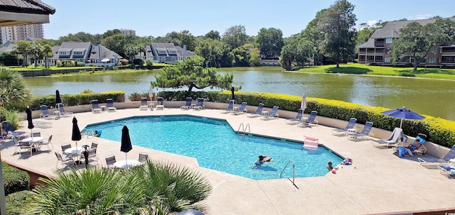 view of swimming pool with a patio area, a water view, and a lawn