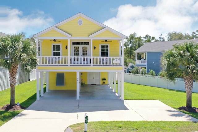 beach home with a balcony, a front lawn, a carport, and ceiling fan