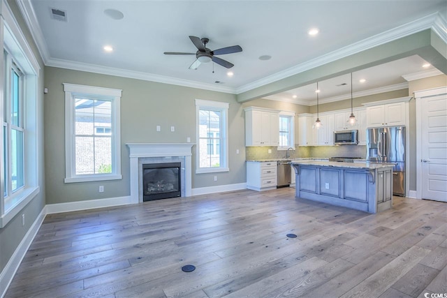 kitchen featuring white cabinets, appliances with stainless steel finishes, pendant lighting, and a center island