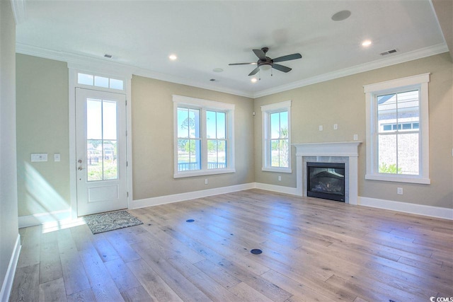 unfurnished living room featuring ceiling fan, light hardwood / wood-style flooring, a tiled fireplace, and a wealth of natural light